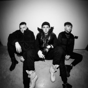 Black & White image of three men sat on the ground